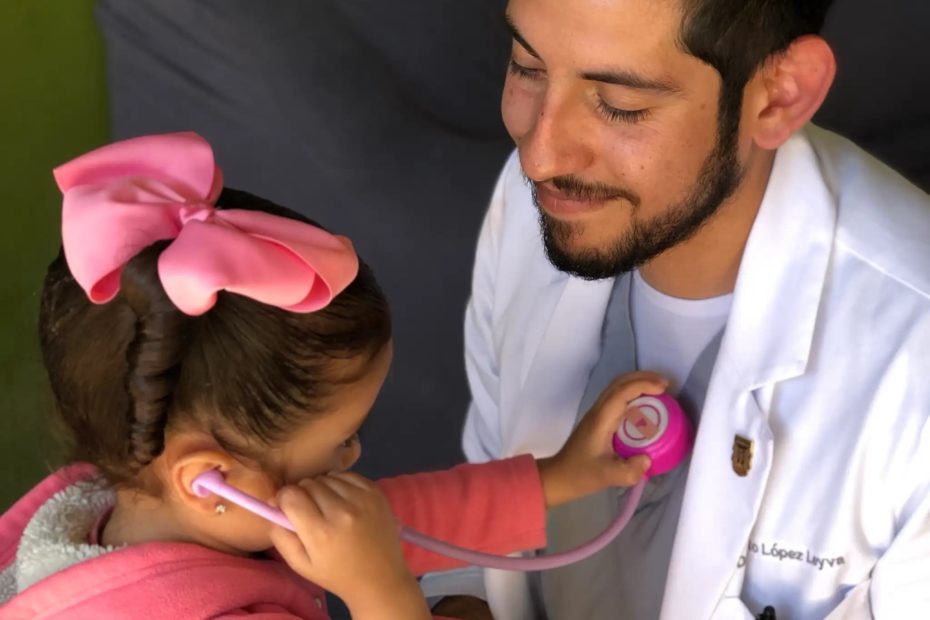 Pediatrician letting a girl test him with stethoscope toy