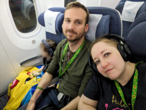 Tessa and their family are sitting on an airplane while wearing their Sunflower lanyards.