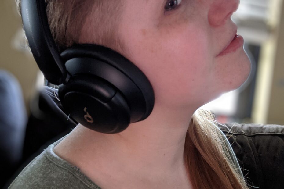 Tessa, a white autistic adult, is wearing a pair of active noise-cancelling headphones