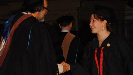 Tessa Watkins is shaking the hand of Game Art & Design department chair, Hans Westman, while crossing the stage at Soldiers & Sailors Memorial Hall at the graduation ceremony for the Art Institute of Pittsburgh.
